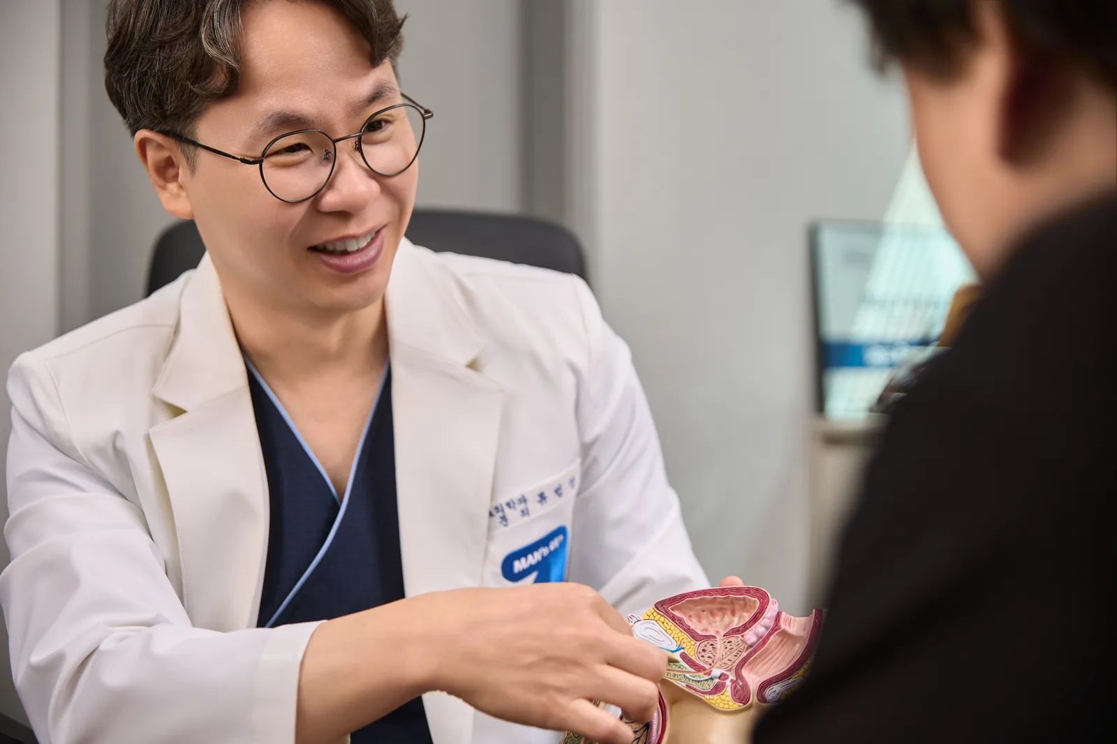 류범상 원장이 흰 가운 차림으로 해부 모형을 손에 든 채 환자를 보며 이야기하는 모습